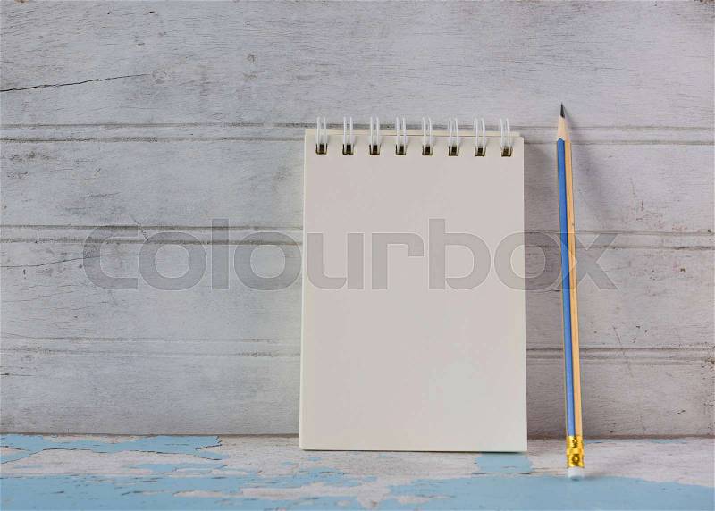 Notebook and yellow pencil on vintage blue wooden table background, stock photo