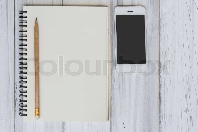Memo notebook,pencil and mobile phone on white wooden table top background,work space concept,top view, stock photo