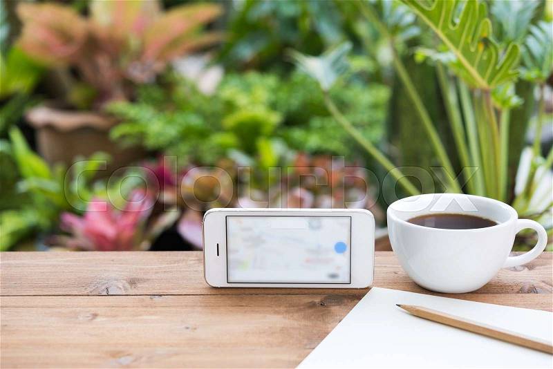 Travel plan,mobile phone,coffee cup,paper and pencil on wooden table in green garden outdoor, stock photo