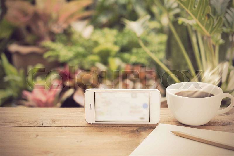 Travel plan,mobile phone,coffee cup,paper and pencil on wooden table in green garden outdoor, stock photo
