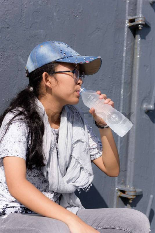 Cute asian girl in trendy style drinking water in sunny day, stock photo