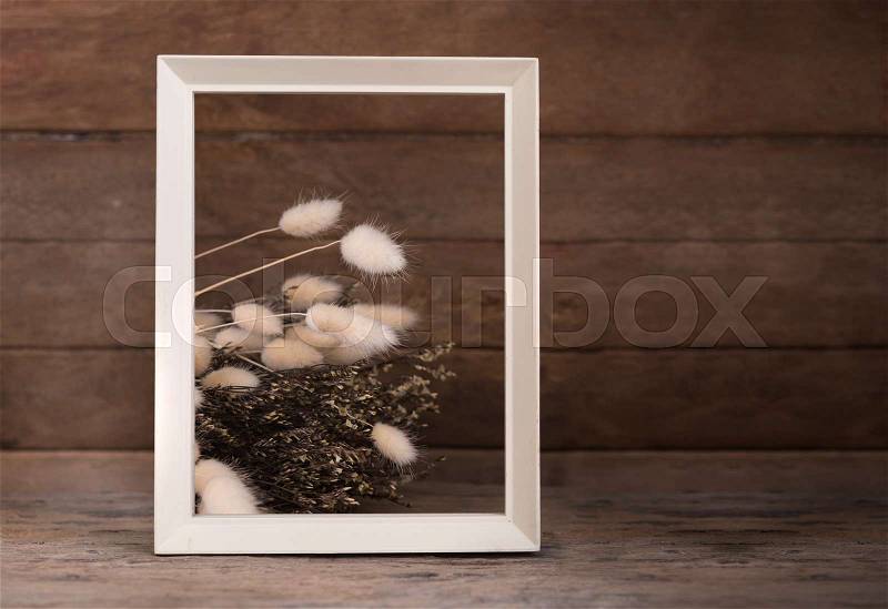 White picture with dried flowers on wooden table top background, stock photo