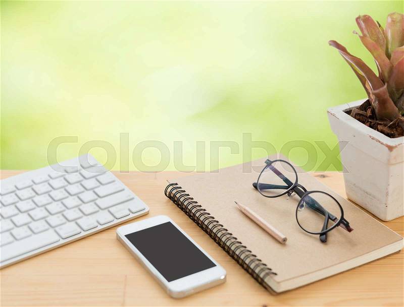 Minimal workspace,computer,smartphone,eyeglasses notebook,pencil on wood table with green blurred background, stock photo