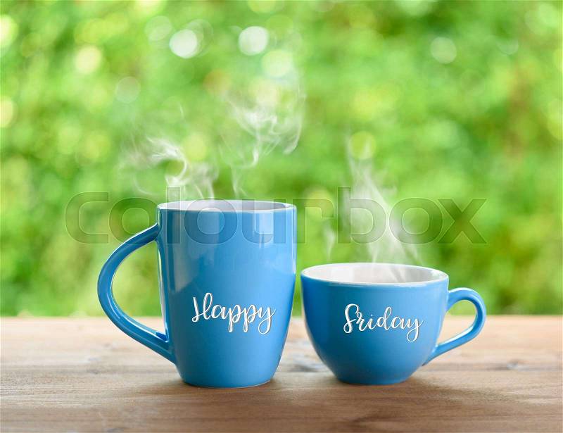 Blue Coffee cups and Happy Friday Quote on nature green blurred background, stock photo