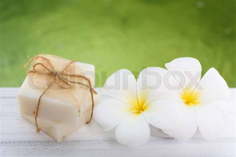Spa milk soap and Frangipani flowers on white wood table with green pond background, stock photo