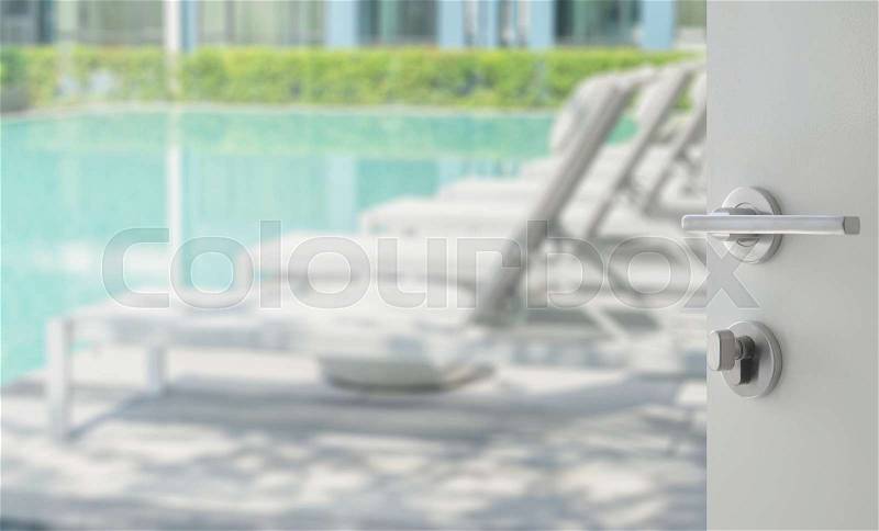 Opened white door to swimming pool with beach chairs, stock photo