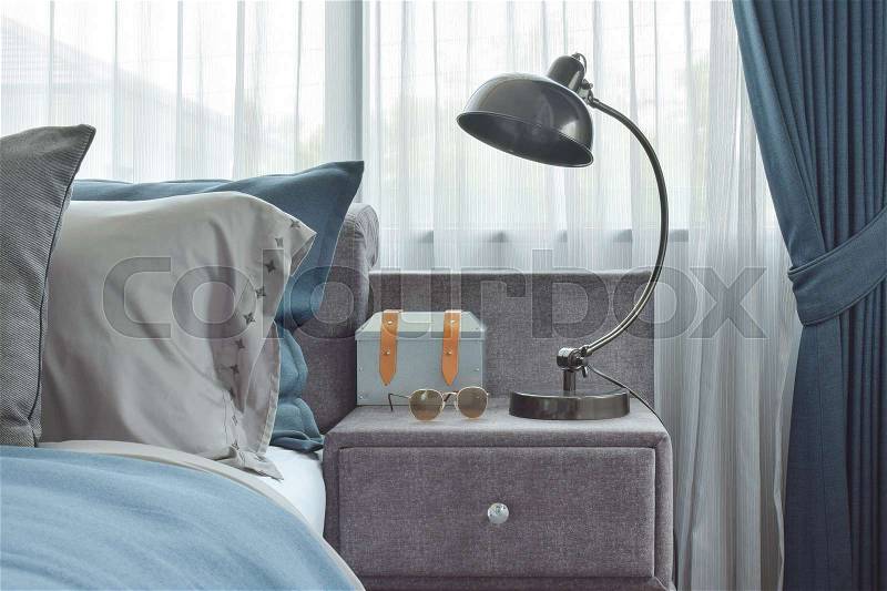 Industrial style reading lamp next to blue color scheme bedding, stock photo
