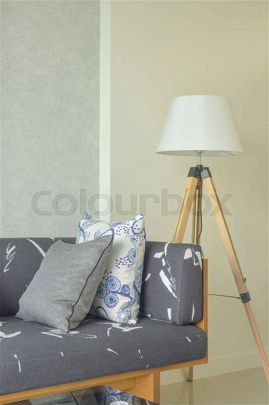 Wooden base with gray upholstery sofa and white shade wooden floor lamp, stock photo