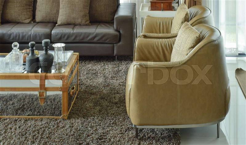 Light brown leather armchairs and dark brown leather sofa in the living room with area rug, stock photo