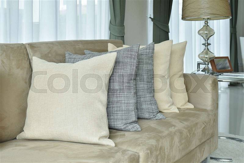 Earth tone pillows setting on light brown sofa in the living room, stock photo