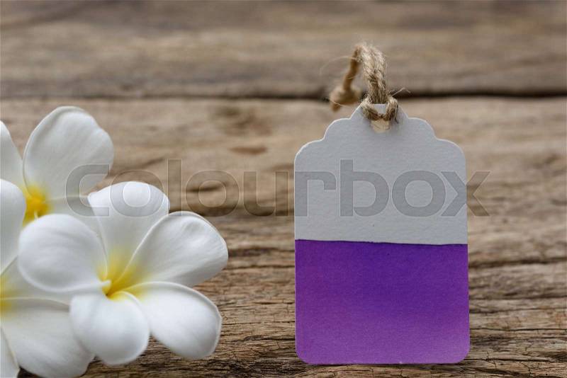 Water color painted on tag label decorate with plumeria flowers on wood table, stock photo