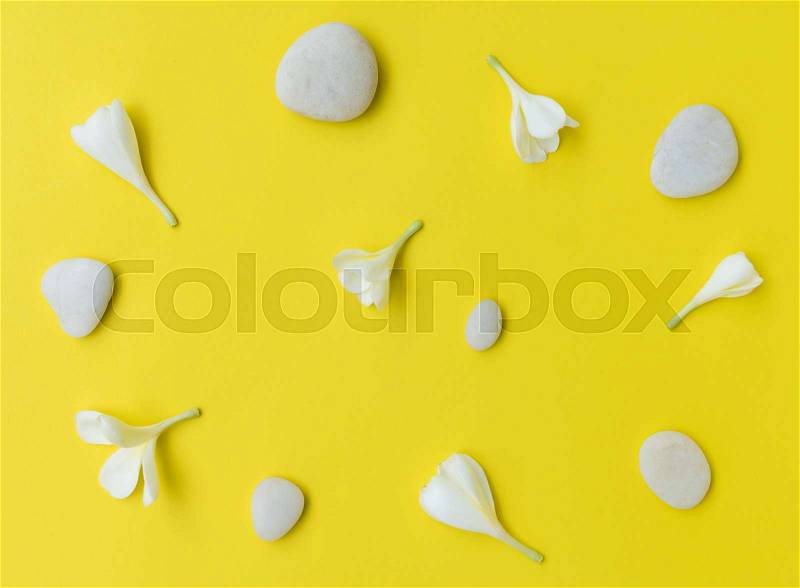 Flat lay white zen stones and Frangipani flower on yellow background,top view, stock photo