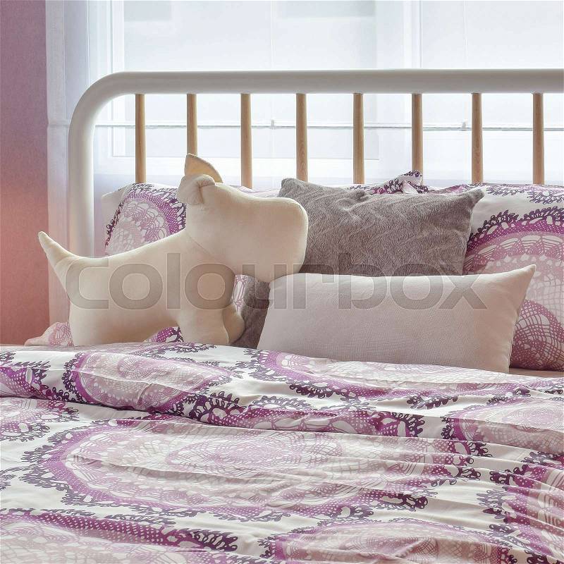 Cozy bedroom interior with puppy doll and pink pillows on bed, stock photo