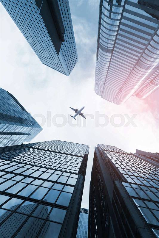 Modern skyline with passenger plane flying over business skyscrapers, high-rise office buildings of Hong Kong city, stock photo