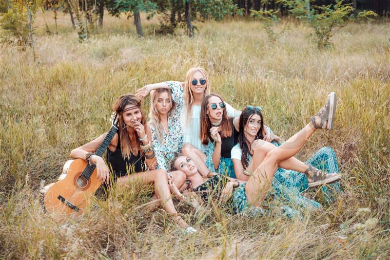 Six girls in nature are sitting on the grass. Have fun, stock photo
