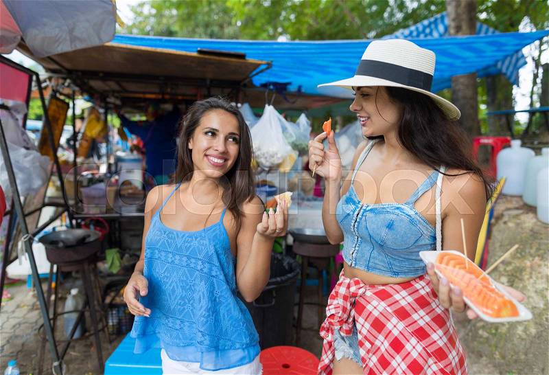 Two Women Tourists Eat Fresh Fruits Happy Smiling Walking Streets In Asian City Young Attractive Girls On Vacation In Asian Country, stock photo