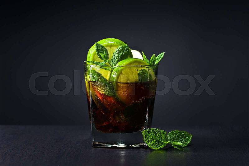 Cola with lime , ice and peppermint on black table in bar, stock photo