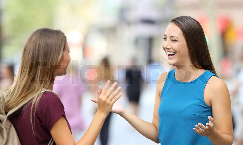 Two happy friends greeting and meeting on the street, stock photo