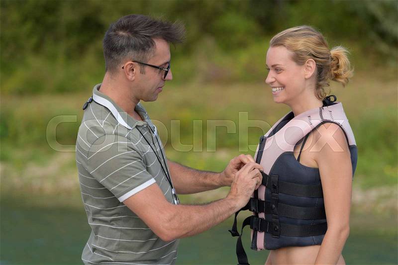 Woman wearing a life jacket before water skiing lesson, stock photo