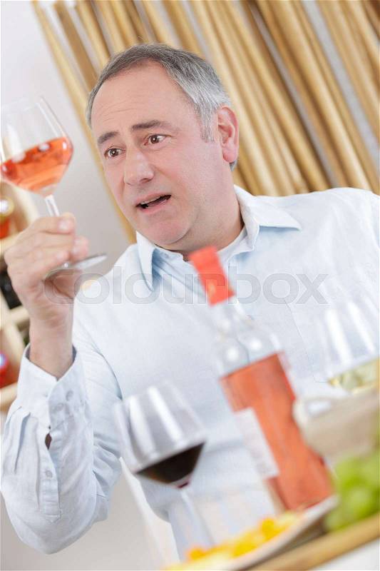 Older tourist drinking a glass of rose in a restaurant, stock photo