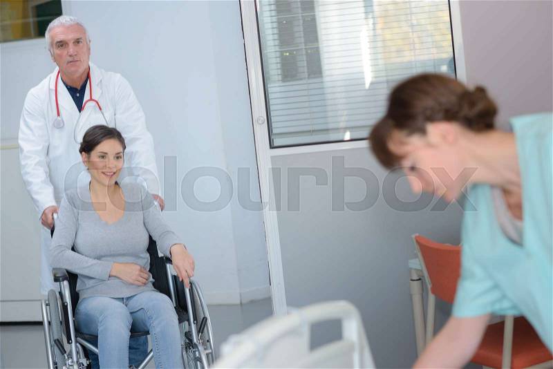 Doctor pushing patient in a wheelchair, stock photo