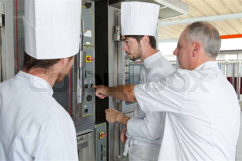 Team of bakers cooking dough in a commercial kitchen, stock photo