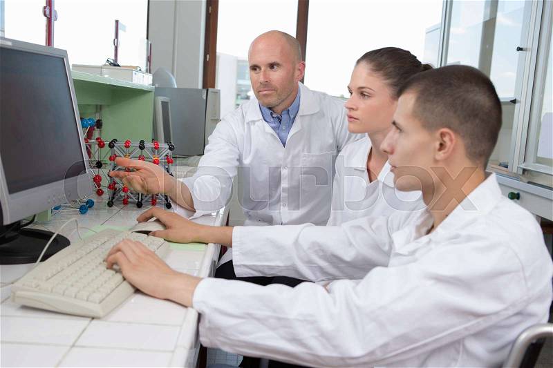Teacher and students at a desk with a computer, stock photo