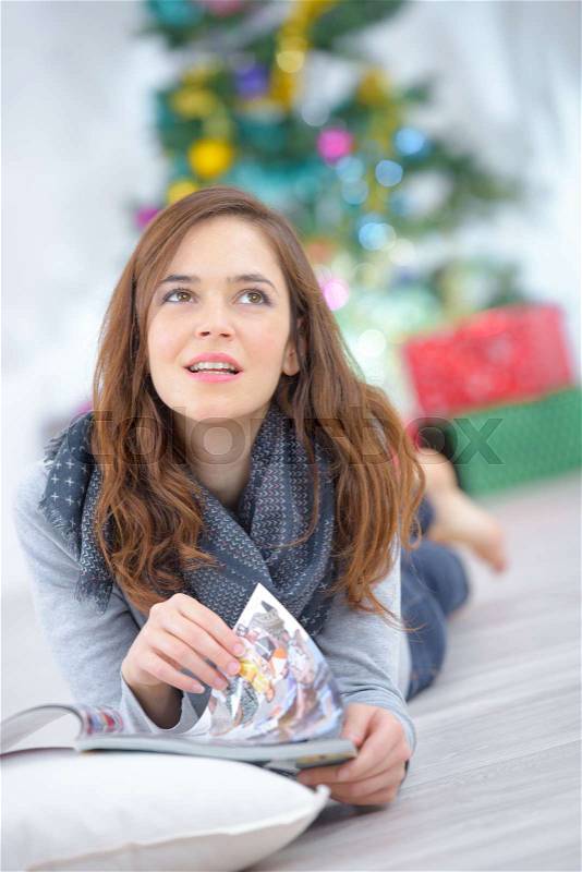 Woman laying on the floor reading a magazine, stock photo