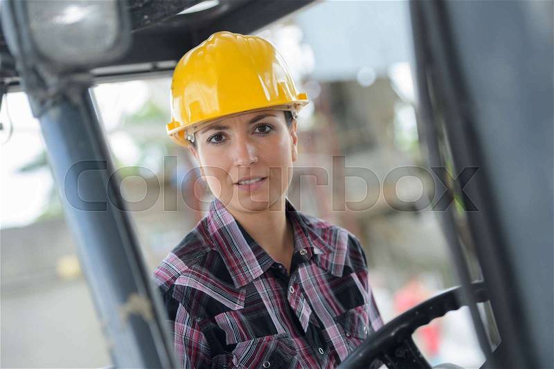 Portrait of female fork lift truck driver in factory, stock photo