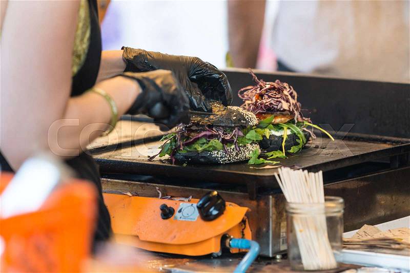 Chef making beef burgers outdoor on open kitchen international food festival event. Street food ready to serve on a food stall, stock photo