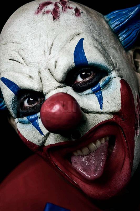 Closeup of a scary evil clown taking out his tongue, stock photo