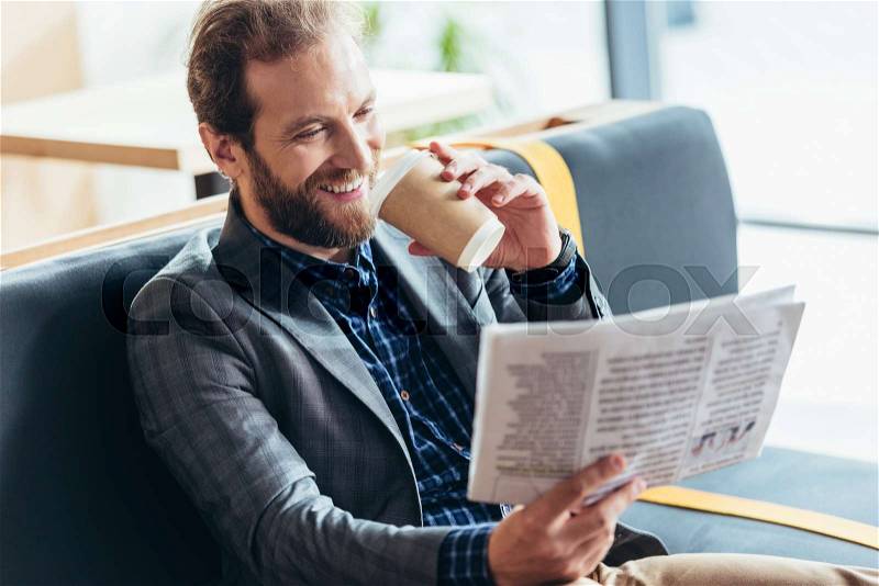 Handsome smiling middle aged man reading newspaper and drinking coffee in cafe, stock photo