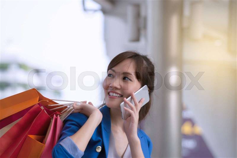 Asian woman shopping smile and holding shopping bag with cell phone, consumerism, sale and people online concept, stock photo