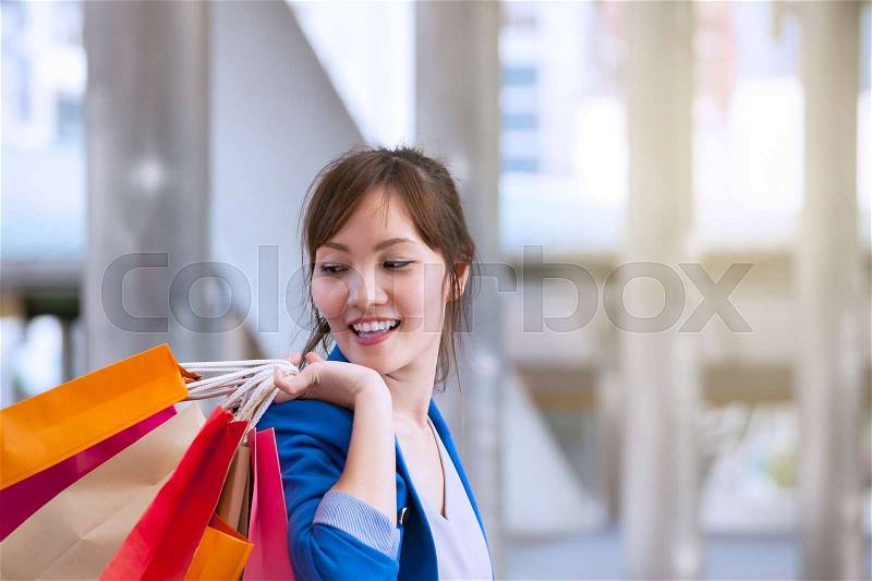 Asian woman shopping smile and holding shopping bag with shopping mall background, consumerism, sale and people online concept, stock photo