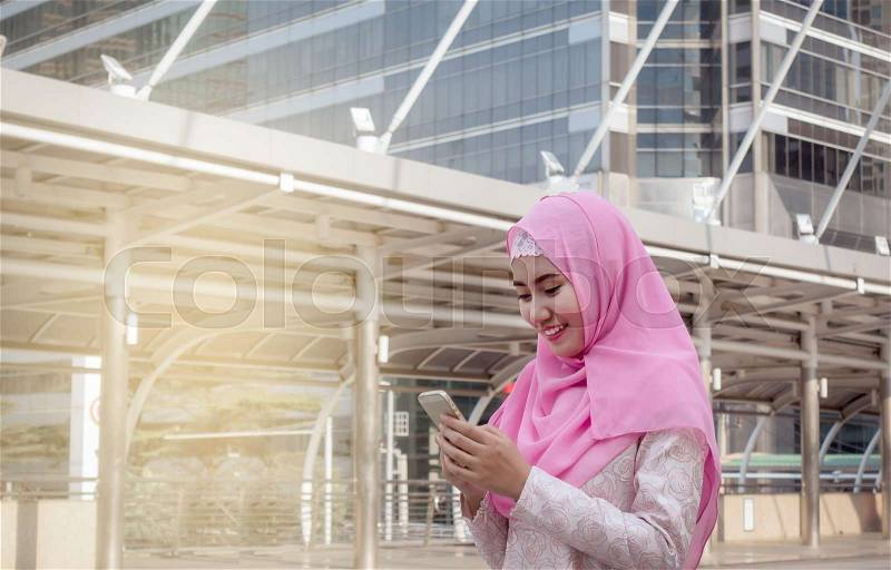 Arabian business woman smiling happy to use cell phone and modern business city background, stock photo