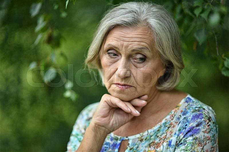Nice sad old woman on the spring background, stock photo