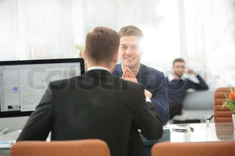 Two men discuss the growth of the company, looking at the rising graph on a computer screen, stock photo