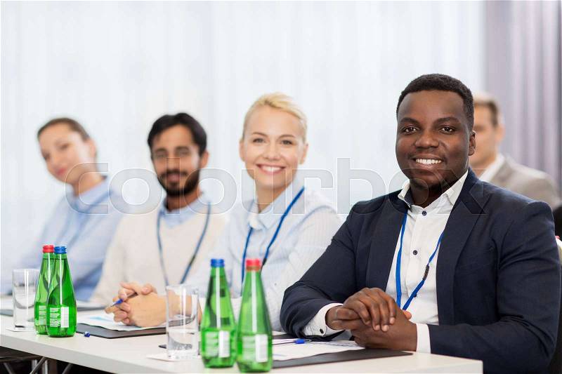 Business and education concept - group of happy people at international conference, stock photo