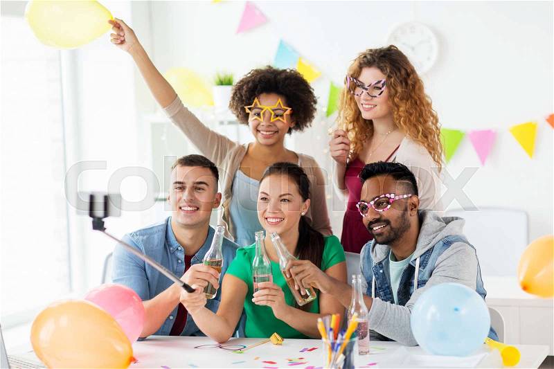 Corporate, celebration and holidays concept - happy friends or team with party accessories taking selfie at office, stock photo