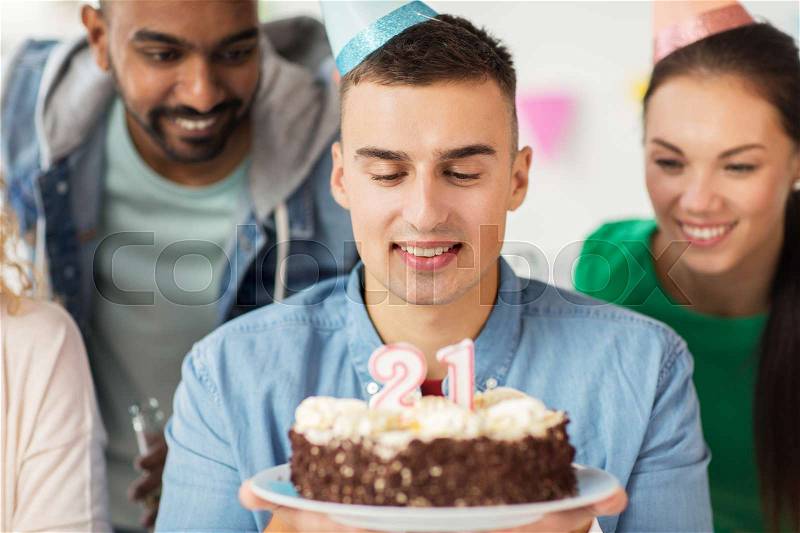 Corporate, celebration and people concept - close up of happy man with birthday cake and team making wish at office party, stock photo