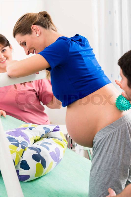 Woman laboring in delivery room with nurse and husband before birth, stock photo