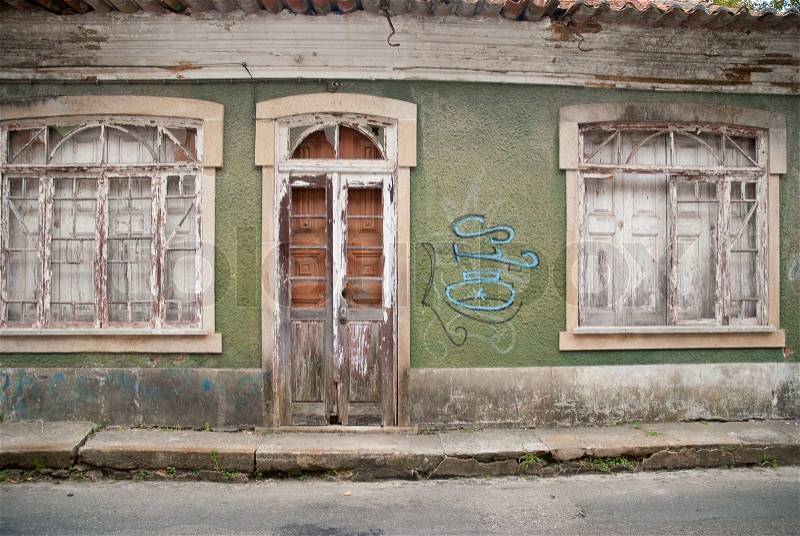 Old house facade with broken door and windows, stock photo