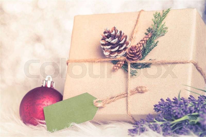 Brown paper craft warped on present box with label tag decorate with pine cone and green leaf christmas ball at sparkling bokeh backgrond,Gift giving for holiday seasonal concept, stock photo