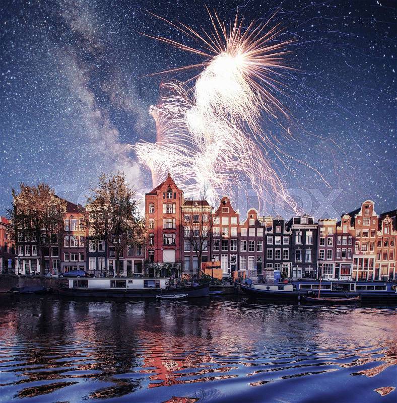 Beautiful night in Amsterdam. Night illumination of buildings and boats near the water in the canal. Photo greeting card. Colorful fireworks on the black sky background , stock photo