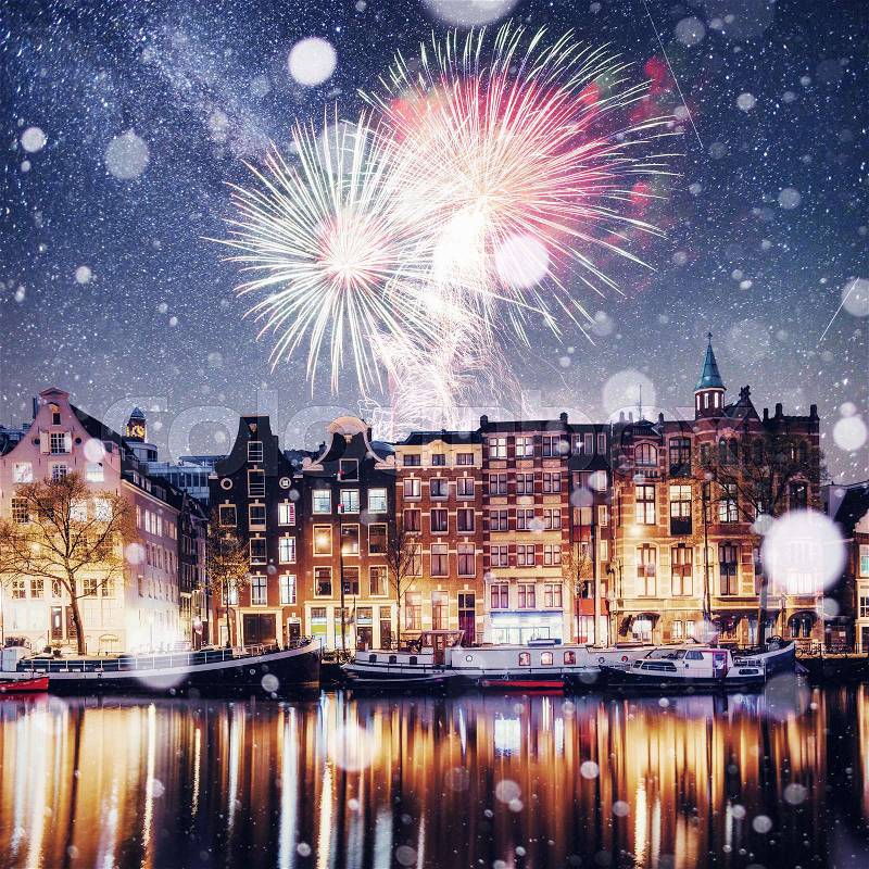 Beautiful night in Amsterdam. Night illumination of buildings and boats near the water in the canal. Photo greeting card. Colorful fireworks on the black sky background , stock photo