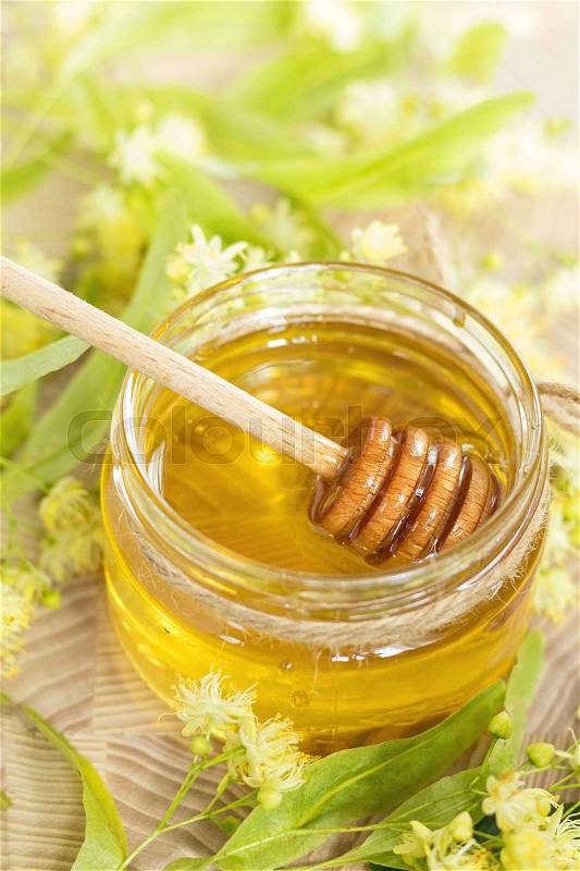 Honey in glass jars with white linden flowers on light wooden background. Shallow depth of field, stock photo