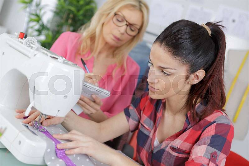 Two beautiful female tailors working in the tailor shop, stock photo