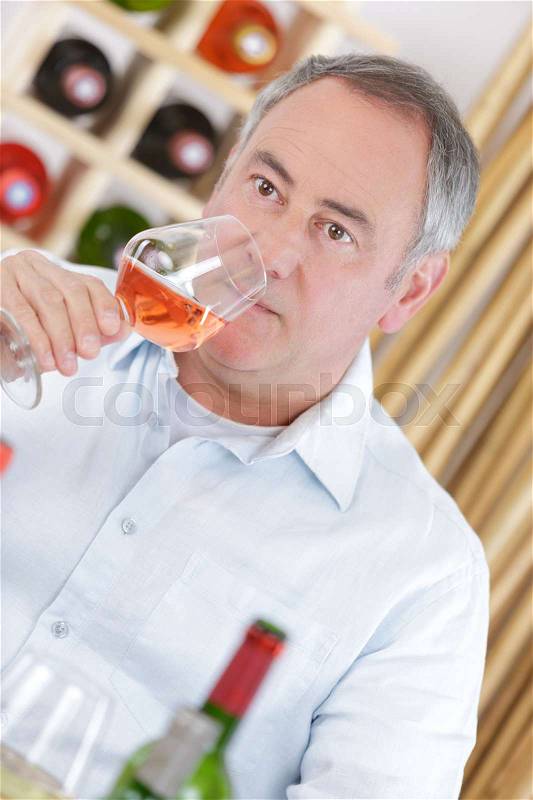 Happy mature man drinking rose wine, stock photo