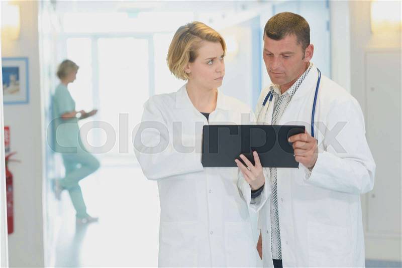 Doctors with clipboard and tablet pc computer at hospital corridor, stock photo