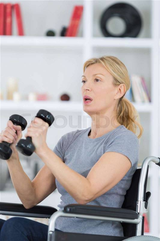 Patient lifting dumbbell in clinic, stock photo